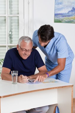 Mature Man playing Sudoku Puzzle clipart