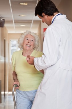 Doctor helping Patient use Walking Stick clipart