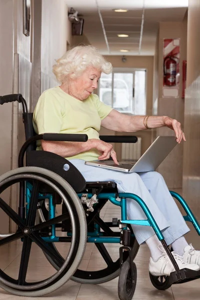 Femme en fauteuil roulant utilisant un ordinateur portable — Photo