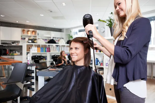 Friseur trocknet Kunden die Haare — Stockfoto