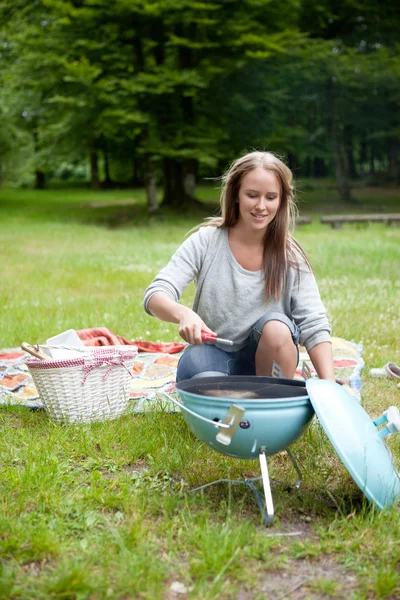 Jeune femme allumant un barbecue — Photo