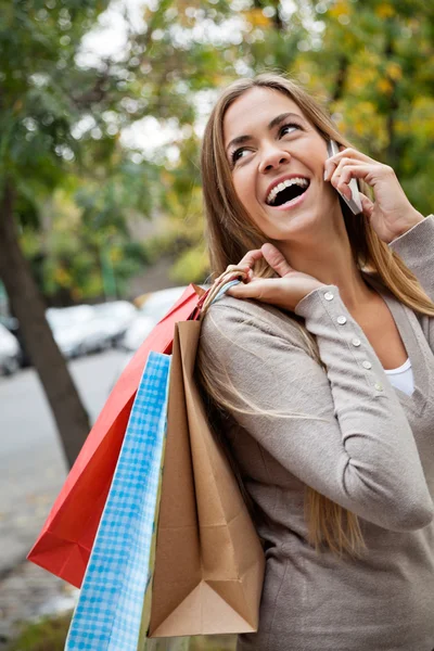 Mujer en una llamada mientras lleva bolsas de compras —  Fotos de Stock