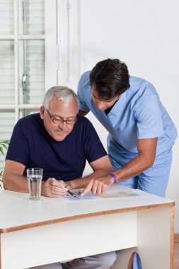 Mature Man playing Sudoku Puzzle clipart