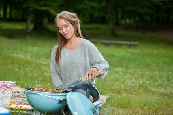 年轻女性烹饪上烧烤的食物 — 图库照片