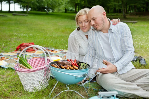 Äldre par matlagning på en utomhus picknick — Stockfoto
