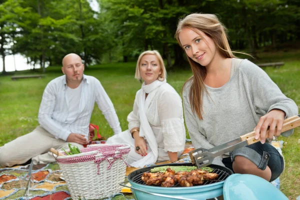 Vrouwelijke koken van vlees op draagbare barbecue — Stockfoto