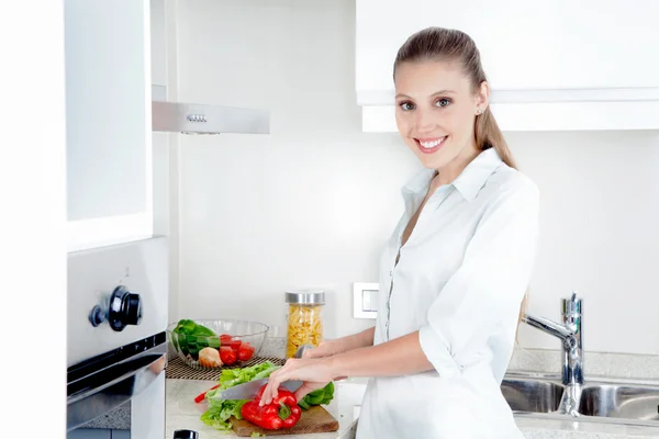 Hezká žena řezání zeleniny v kuchyni — Stock fotografie