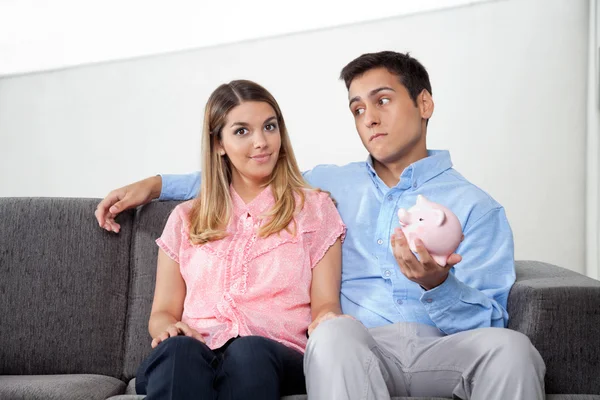 Hombre holding piggybank mientras sentado con mujer — Foto de Stock