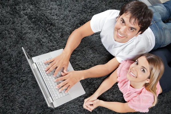 Casal no tapete com laptop — Fotografia de Stock