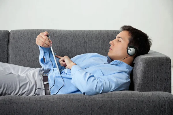 Розслаблений чоловік слухає музику на цифровому планшеті — стокове фото