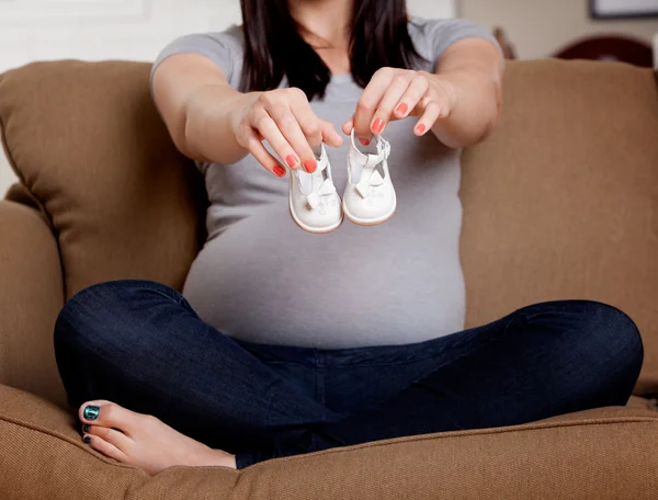 Těhotná žena drží dětské boty — Stock fotografie