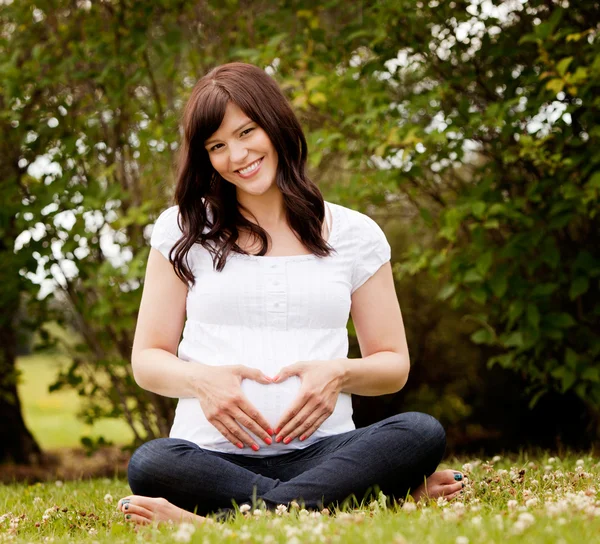 公園で幸せの笑みを浮かべて妊娠中の女性 — ストック写真