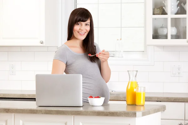 Zwangere vrouw in keuken eten ontbijt — Stockfoto