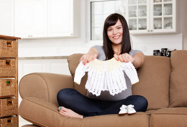 Verwacht moeder met kleren van de baby — Stockfoto