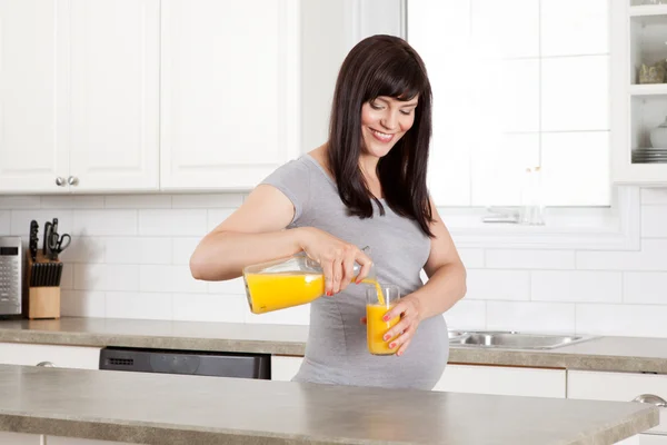 Donna incinta versando succo d'arancia — Foto Stock