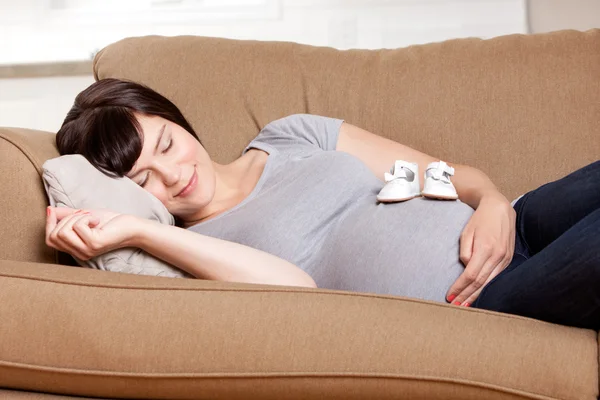 Беременная мать отдыхает на диване — стоковое фото