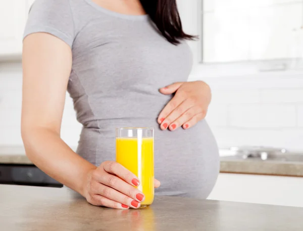Gravid kvinna anläggning orange juice — Stockfoto