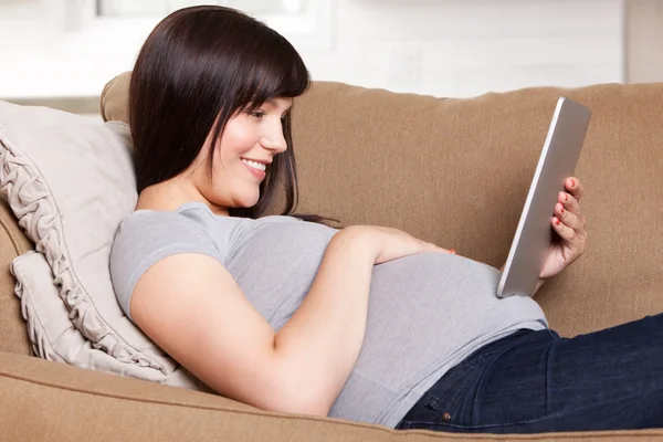 Щаслива вагітна жінка з цифровим планшетом — стокове фото