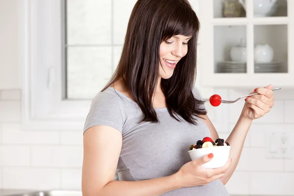 Беременная женщина ест свежие фрукты — стоковое фото