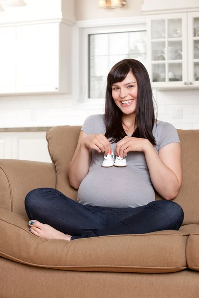 Mujer embarazada feliz sosteniendo zapatos de bebé — Foto de Stock
