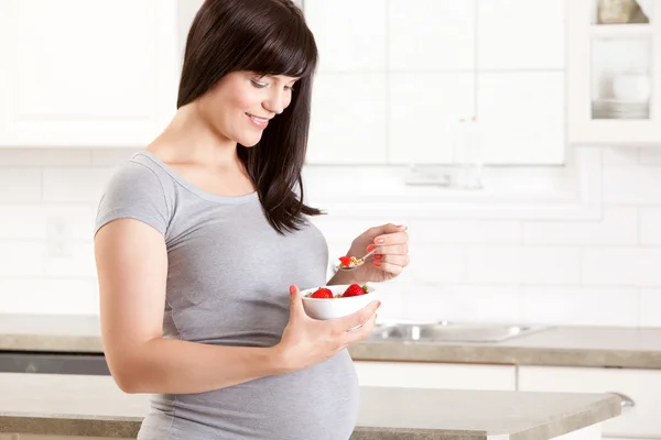 Těhotná žena v kuchyni, jíst zdravou svačinu — Stock fotografie