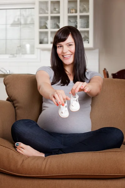 Беременная женщина в детской обуви — стоковое фото