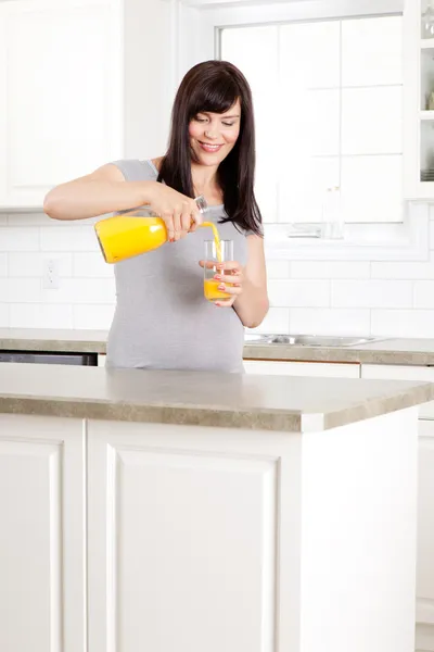 Donna incinta versando succo d'arancia — Foto Stock