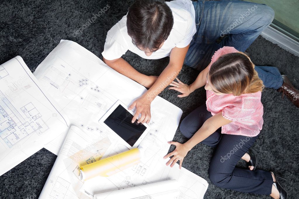 Couple Sitting On Rug With House Plans