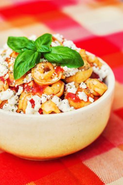 Tortellini with tomato sauce, decorated with basil clipart