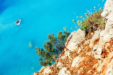 The beautiful turquoise waters of Porto Katsiki as seen from the edge of a cliff clipart