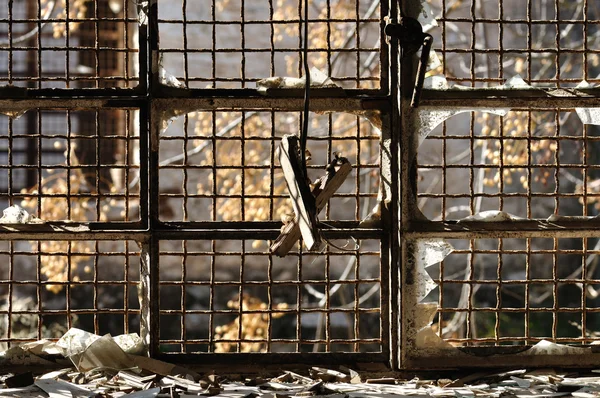 Rozbité okno rezavý drátěné pletivo — Stock fotografie