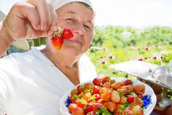 The elderly woman shows a crop - strawberry — Stock Photo, Image