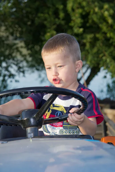 The boy drives a small tractor — Stock Photo, Image