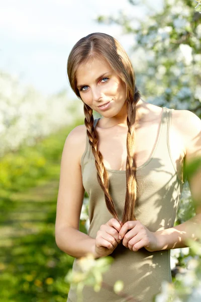 Beautiful young woman standing near the apple tree on a warm sum — Stock Photo, Image