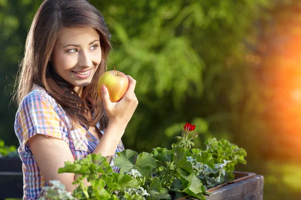 Portrait of girl with red apple against green garden. — Stock Photo, Image