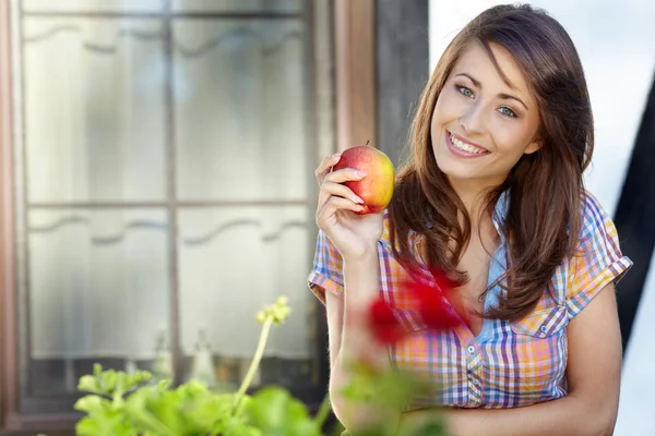 Porträtt av flicka med rött äpple mot grön trädgård. — Stockfoto
