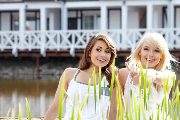 Dois jovens mulheres bonitas em um parque um deles aponta em algo — Fotografia de Stock