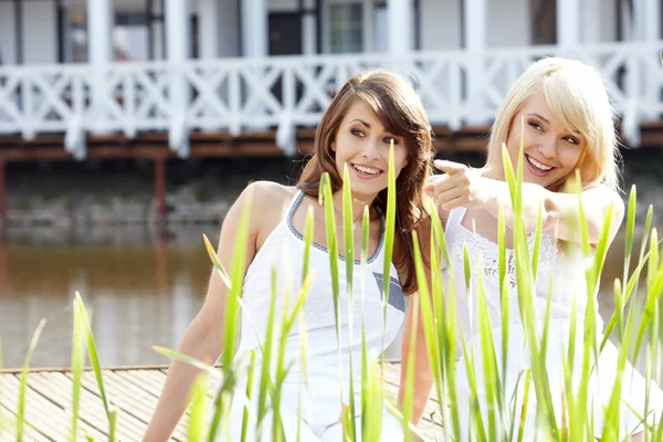 Twee youngl mooie vrouwen in een park een van hen wijst op somethin — Stockfoto