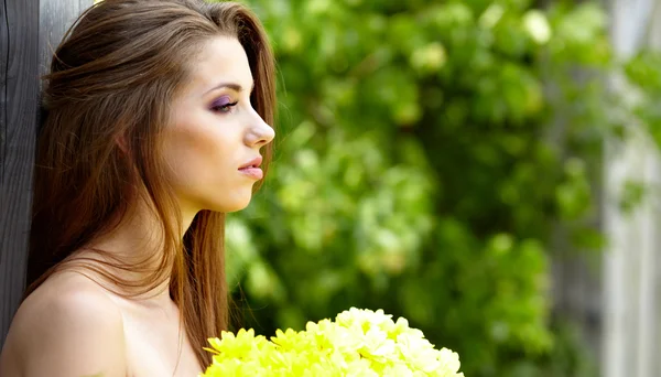 Mujer sosteniendo flores amarillas. disparar al aire libre — Foto de Stock