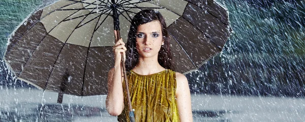 Hermosa mujer sosteniendo el paraguas bajo la lluvia — Foto de Stock