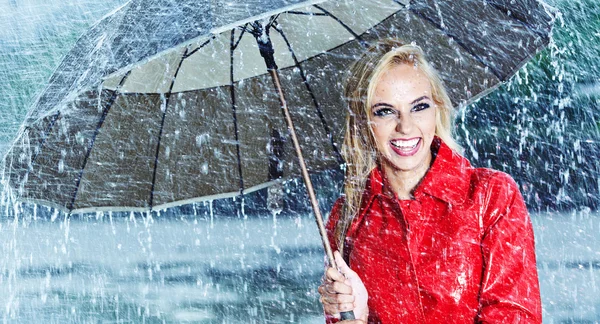 Beautiful blonde woman holding umbrella out in the rain — Stock Photo, Image