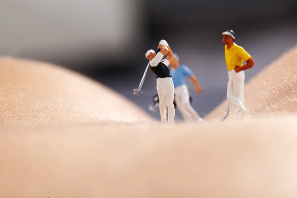 Figuras en miniatura jugando al golf en cuerpo de mujer desnuda — Foto de Stock