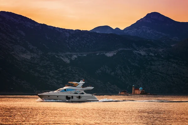 Швидкісний човен на морі заходу сонця на фоні гір — стокове фото