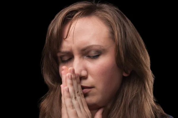 Jovem mulher está orando contra fundo escuro — Fotografia de Stock