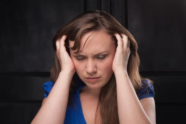 Mädchen mit Kopfschmerzen auf dunklem Hintergrund Stockbild
