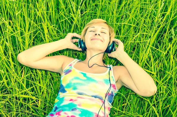 Ung kvinna med hörlurar på fältet — Stockfoto