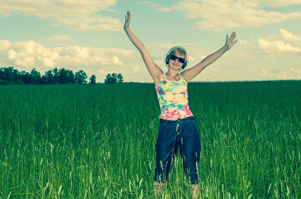 Молодая женщина в наушниках на поле — стоковое фото