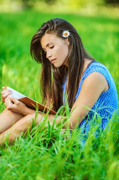 Frau sitzt auf Gras und liest Buch — Stockfoto