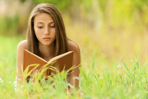 女人躺在草读的书 — 图库照片
