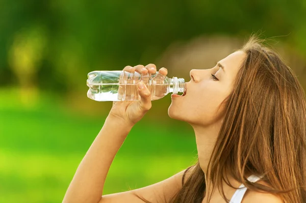 Mujer joven bebiendo botella de agua — Foto de Stock